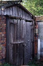 Garden shed with brick walls and an old weathered wooden door and front facade