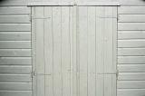 Garden wooden shed doors painted white viewed from the front in full frame background image