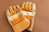 Pair of old used gardening gloves lying on a brown background with copyspace