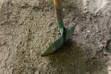 Green metal garden spade or shovel standing upright in soil viewed from above with copyspace