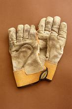 Pair of used gardening gloves lying on a brown background, overhead view