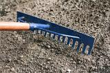 Soil preparation in the garden with a blue metal rake on a portion of finely raked and leveled soil ready for planting