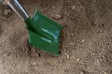 High angle view of a green garden shovel or spade resting on soil in the garden in preparation for spring planting