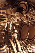 Detail of the interior of a dishwasher showing a range of clean crockery and cutlery