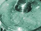Boiling pot of water on a stove with a glass lid so that the bubbles are visible