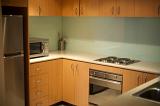Neat clean kitchen with a built in under counter oven, microwave and wooden cabinetry