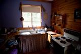 Interior of a cottage kitchen with rustic wooden countertops and curtained units