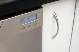 Programmable digital display on the front of a modern metallic dishwasher in the kitchen for washing dirty crockery and glassware