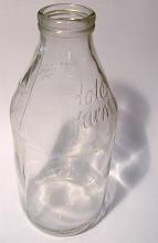 Empty glass milk bottle in the traditional shape with text for reuse and refilling for household consumption