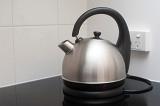Modern silver metal cordless domed domestic kettle standing on its base on a kitchen countertop