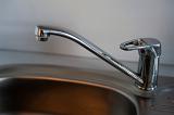 Detail of a modern chrome mono block kitchen tap over a stainless steel kitchen sink