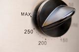 Closeup of a circular oven thermostat control knob with various temperature settings for cooking