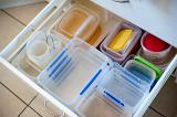 Open drawer in a kitchen unit used for storage and filled with neatly arranged plastic storage containers for food