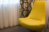 Stylish retro styled yellow bucket chair in a modern living room with bold patterned drapes in an interior decor concept