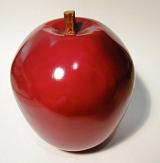 Close-up of a shiny red ceramic decorative apple, with shadow, on light grey background