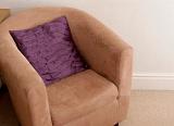 Comfortable empty upholstered brown curved armchair with a cushion, close up view