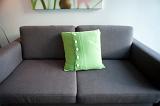 a plain grey sofa with a single green cushion and lots of space for copy