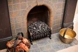 Fireplace with coal or anthracite in the old-fashioned metal grate in the hearth and old brass cauldrons with wood and cones on either side