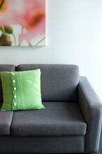 Green cushion on a vacant modern upholstered grey couch, close up view