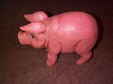 Naturalistic carved cute pink wooden pig ornament, high angle view standing sideways to the camera with its ears cocked forwards