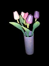 Ornamental colorful purple, pink and white spring tulips arranged in a cylindrical vase on a dark background