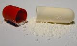 Close Up of Broken Open Red and White Pill Capsule on White Background with White Medication Powder Spilled Out