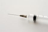 Needle on a disposable plastic syringe over a grey background with copy space conceptual of injecting medication or drug addiction