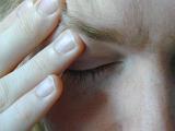 Close Up of Person with Eyes Closed Rubbing Forehead Above Eye with Hand as if Stressed or Experiencing Headache