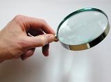 Close Up of Hand Holding Magnifying Glass, Searching for Clues on White Background