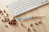 medical analysis concept, a syringe, and some tablets with a computer keyboard on wooden desk