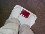 Man in his socks standing on a medical scale, high angle view looking down at the digital readout between his toes