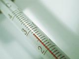 Mercury-in-glass cylindrical thermometer measuring a temperature of 28 grades, close-up with shadow and copy space on grey