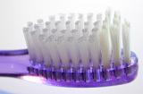 Head of a purple plastic toothbrush with new bristles in a dental care, oral hygiene and medical concept