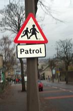Traffic warning sign for a school crossing and patrol on a pole at the side of an urban street
