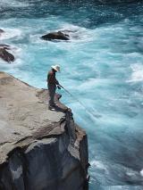 a man fishing from the top of a tall cliff