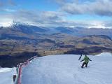 two snowboarders race down the piste in newzealand