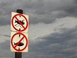 two signs marking a no fishing area against a backdrop of storm clouds