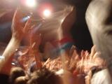 excited fans waving their hands in the air at a rock concert