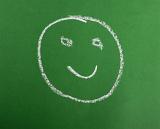 a smiling happy face drawing in chalk on a green background
