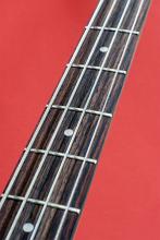 the neck, strings and frets on a bass guitar pictured against a red background