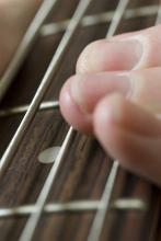 finger playing a bass guitar