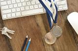 office achievement award with a keyboard and two winners medals on a blue lanyard