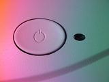 White oval power button with standby or power symbol viewed in graduated pink through green light