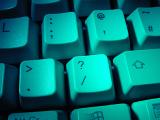 A green lit question mark key on a computer keyboard