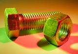 Close up detail of a threaded steel bolt and nut in colorful lighting casting a red shadow with copy space