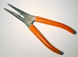 Pliers with red handles framed diagonally and viewed in close-up on white surface background