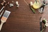 Assorted arts and crafts tools scattered around the edges of wooden desk surface background