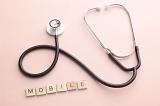 Little blocks spelling the word mobile below professional web development concept with stetoscope over pink background