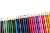 Slanted row of new sharpened colored pencils in green, blue, red, pink and orange with copy space over white