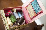 Open sewing box with assorted colored reels of yarn or cotton, pins and needles viewed from above in a handicraft concept